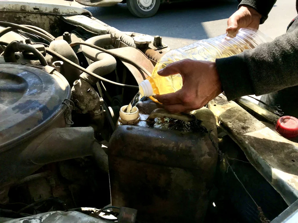 Mechanic topping up coolant in a car engine bay