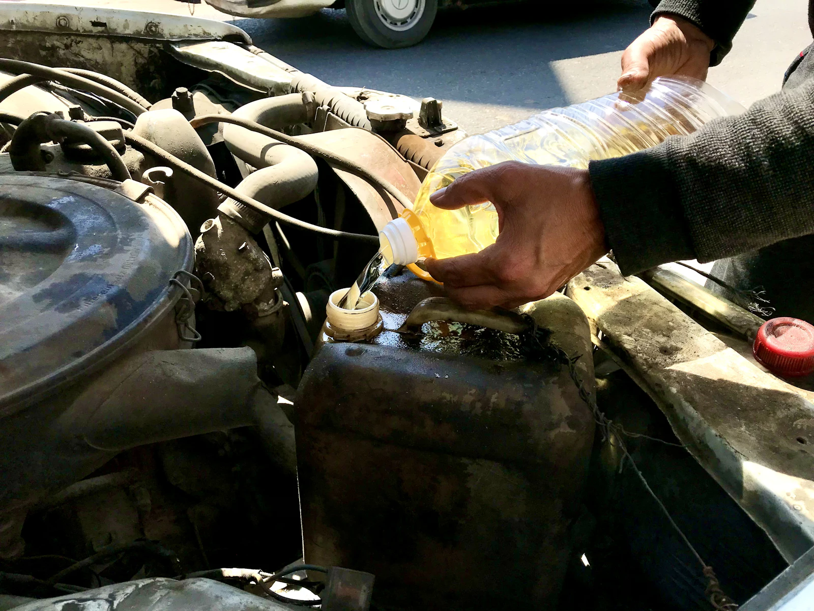 Mechanic topping up coolant in a car engine bay
