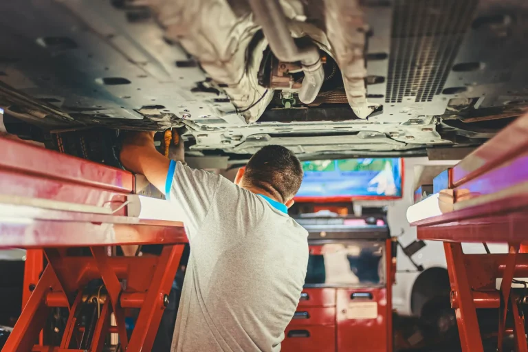 Mechanic inspecting the underside of a car on a ramp